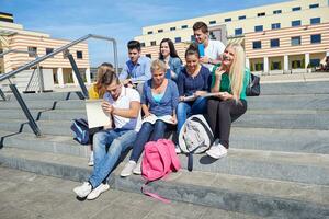 studenten buiten zittend Aan stappen foto