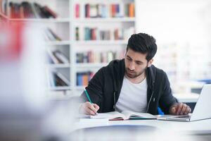 leerling in school- bibliotheek gebruik makend van laptop voor Onderzoek foto