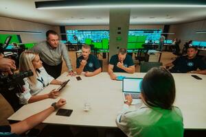 groep van veiligheid bewakers zittend en hebben briefing in de systeem controle kamer zij zijn werken in veiligheid gegevens centrum omringd door meerdere schermen foto