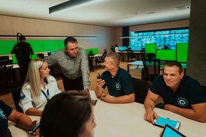 groep van veiligheid bewakers zittend en hebben briefing in de systeem controle kamer zij zijn werken in veiligheid gegevens centrum omringd door meerdere schermen foto