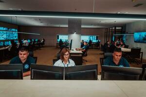 groep van veiligheid gegevens centrum operators werken in een cctv toezicht houden kamer op zoek Aan meerdere monitoren officieren toezicht houden meerdere schermen voor verdacht activiteiten team werken Aan de systeem controle foto