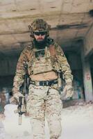 een gebaard soldaat in een speciaal krachten uniform wandelingen door een verlaten gebouw na een geslaagd missie. selectie focus foto
