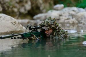 een leger Mens of airsoft speler in een camouflage pak sluipen de rivier- en doelen van een scherpschutter geweer- naar de kant of naar doelwit. foto