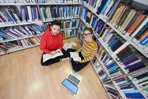 de studenten toepassingen een notitieboekje, laptop en een school- bibliotheek foto