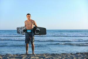 portret van een jong kitsurfen Mens Bij strand Aan zonsondergang foto