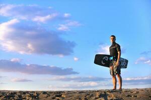 portret van een jong kitsurfen Mens Bij strand Aan zonsondergang foto