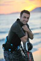 portret van een jong kitsurfen Mens Bij strand Aan zonsondergang foto