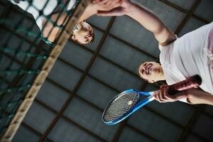 jong meisjes spelen tennis spel binnen- foto