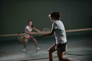 jong meisjes spelen tennis spel binnen- foto