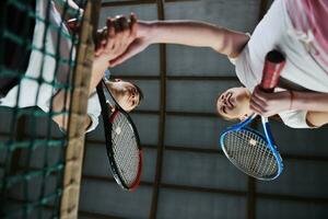 jong meisjes spelen tennis spel binnen- foto