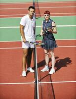 gelukkig jong paar Speel tennis spel buitenshuis foto