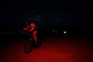 triatlonatleet die 's nachts snel fietst foto