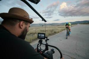 videograaf nemen actie schot van triatlon atleet terwijl rijden fiets foto