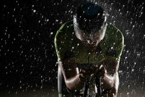 triatlon atleet rijden fiets snel Aan regenachtig nacht foto