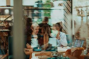 gelukkig mensen uit het bedrijfsleven glimlachen vrolijk gedurende een vergadering in een koffie winkel. groep van geslaagd bedrijf professionals werken net zo een team in een multicultureel werkplek. foto