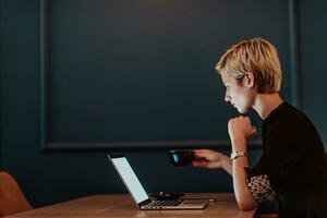 zakenvrouw zittend in koffie winkel Bij houten tafel, drinken koffie en gebruik makend van laptop. zakenvrouw browsen internetten, chatten, bloggen. selectief focus foto