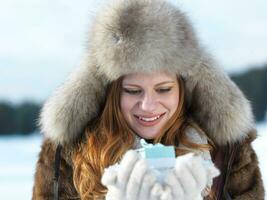 portret van meisje met geschenk Bij winter tafereel en sneeuw in backgrond foto