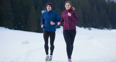 paar jogging buiten Aan sneeuw foto