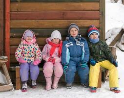 weinig kinderen groep zittend samen in voorkant van houten cabine foto