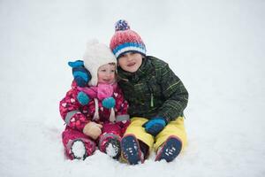 kinderen groep hebben pret en Speel samen in vers sneeuw foto