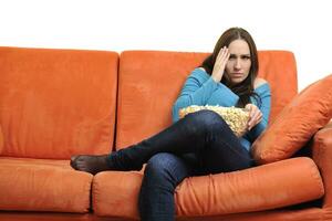 jong vrouw eten popcorn en aan het kijken TV foto