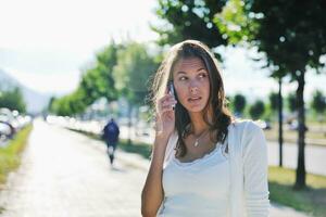 jong vrouw praten door mobiele telefoon Aan straat foto