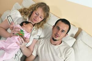 binnen- portret met gelukkig jong familie en schattig weinig schatje foto