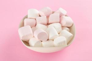 marshmallow in kom op pastelroze achtergrond foto