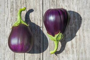 twee aubergines vers fron de tuin zitten Aan een oud hout tafel foto