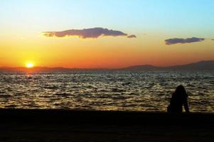 mensen silhouet en de zee bij zonsondergang foto