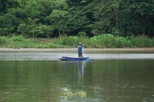eenzame man staat op de boot en haalt de vis uit het net foto