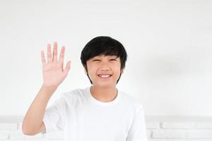 portret Aziatische jongen zwaaiende hand voor begroeting op witte achtergrond foto
