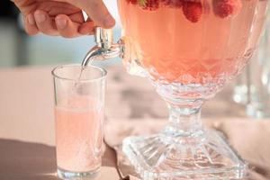 hand gietende limonade uit een blikje met een kraan, aardbeien drijft foto
