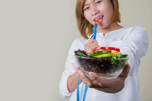 mooie vrouw salade eten met vork meetlint verpakt. foto