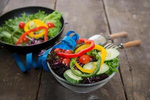 verse groentensalade op kom met het meten van houten achtergrond. foto