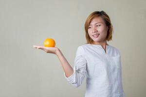 portret van mooie vrouwenglimlach die oranje fruit houdt foto