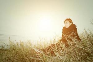 trieste jonge vrouw die op het gras zit en zich zo verdrietig en eenzaam voelt foto