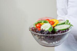 handen van mooie vrouw met grote kom verse vegetarische salade. foto