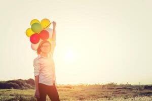 vrouw met een bril met ballonnen in het veld smiley naar camera foto