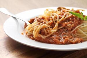 close-up van een vork met spaghetti en rode saus in witte schotel foto