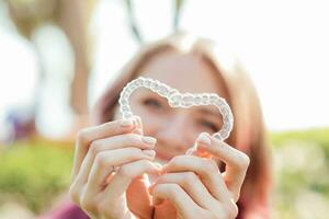 tandheelkundig zorg.glimlachen meisje met een beugel Aan haar tanden houdt aligners in haar handen en shows de verschil tussen hen foto