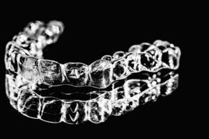 onzichtbaar tandheelkundig tanden haakjes tand aligners Aan zwart achtergrond. plastic een beugel tandheelkunde vasthouders naar rechtzetten tanden. foto