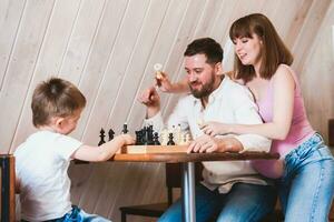 zwanger vrouw aan het kijken vader en zoon Speel schaak Bij de tafel foto