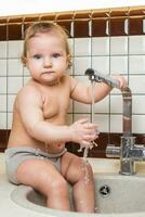 schattig baby spelen in de keuken wastafel foto