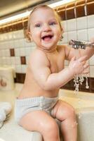 portret van een gelukkig kind wie Toneelstukken en spatten in de keuken wastafel foto
