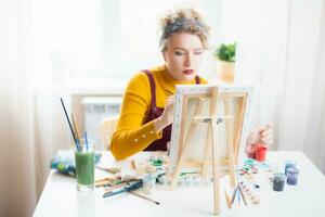 mooi vrouw artiest verven Aan canvas Bij huis foto
