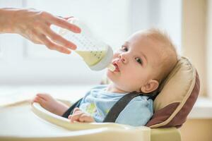 mam is voeden haar baby een fles van melk foto