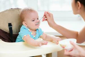 mam feeds haar negen maanden baby Bij huis foto