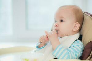 baby Holding een lepel in zijn mond foto