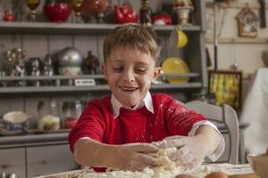 weinig jongen hebben pret en bereiden de deeg voor koekjes foto